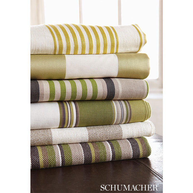 Stack of folded striped linens in olive, cream and green tones with textured weave; Schumacher brand.