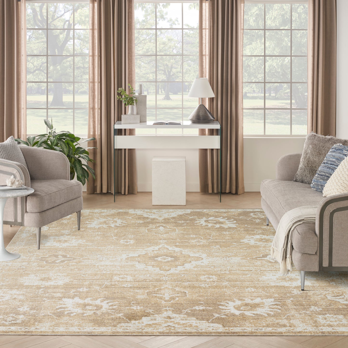 Neutral living room with beige floral area rug, taupe sofas, large windows, and a white console table with lamp.