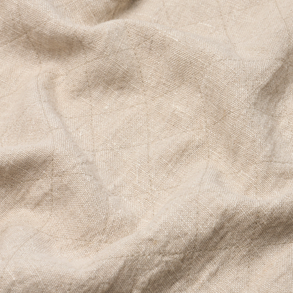 Beige linen-like fabric close-up with visible weave and soft wrinkles; natural, textured material.
