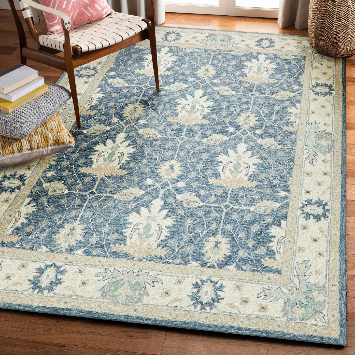 Blue floral area rug with ivory border and pale blue motifs on wood flooring in a cozy living room.