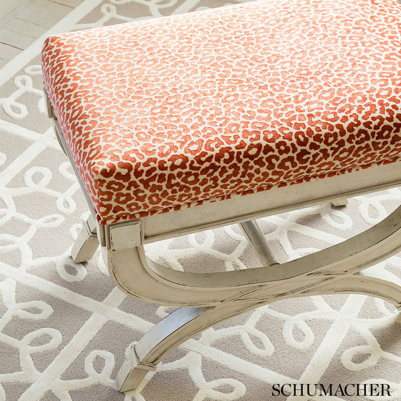 Mid-century modern leopard-print orange and white ottoman with cream curved-metal frame.
