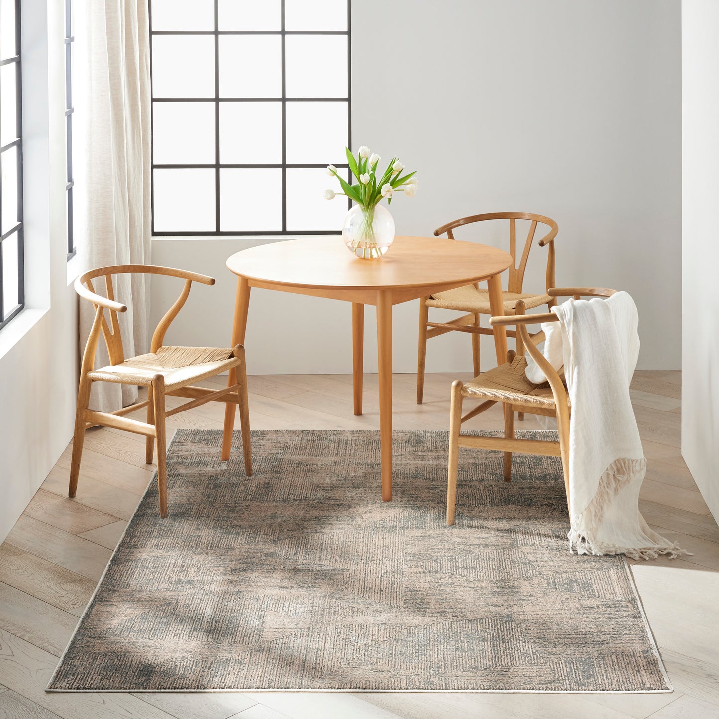 Modern neutral rug 5' x 7' in a bright dining nook, with a light wood dining table and curved-back chairs.