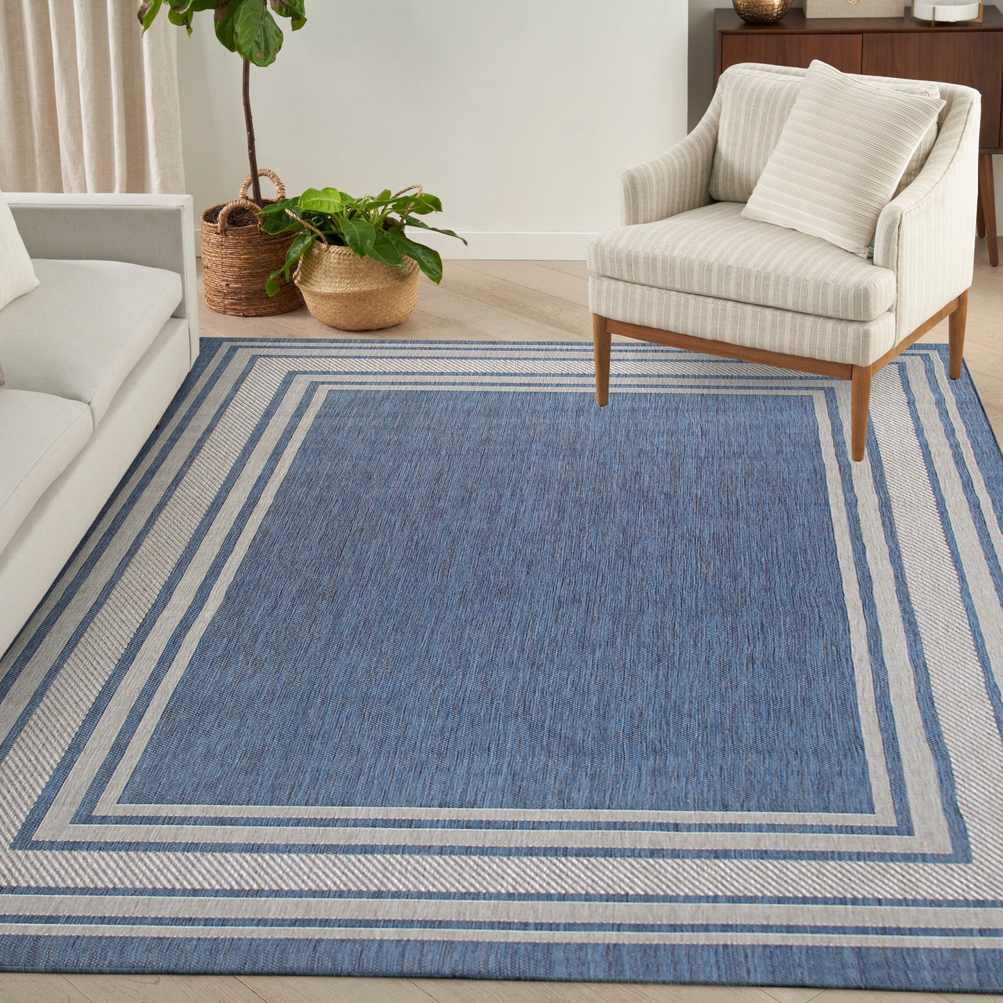 Blue rectangular woven area rug with layered light-blue borders in a modern living room.