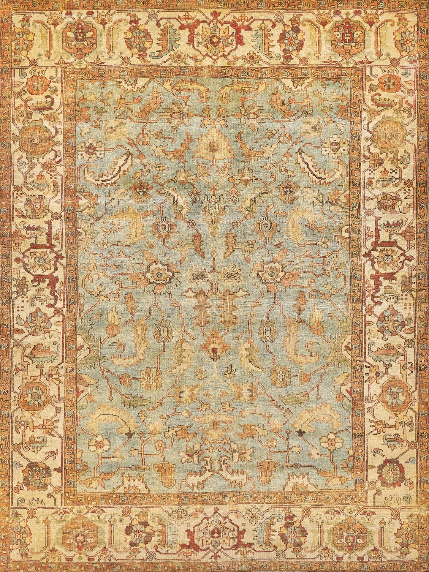 Vintage-style area rug featuring a light blue background with intricate floral and geometric patterns in warm hues of red, gold, and cream.