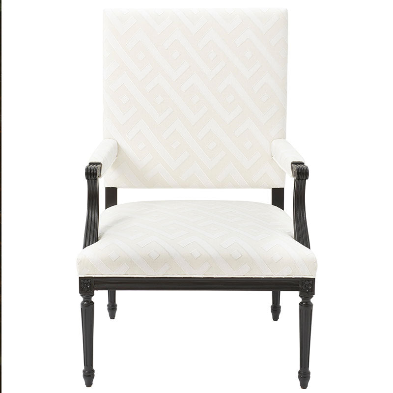 Cream geometric patterned upholstered armchair with tall back, dark carved wood frame and tapered legs.