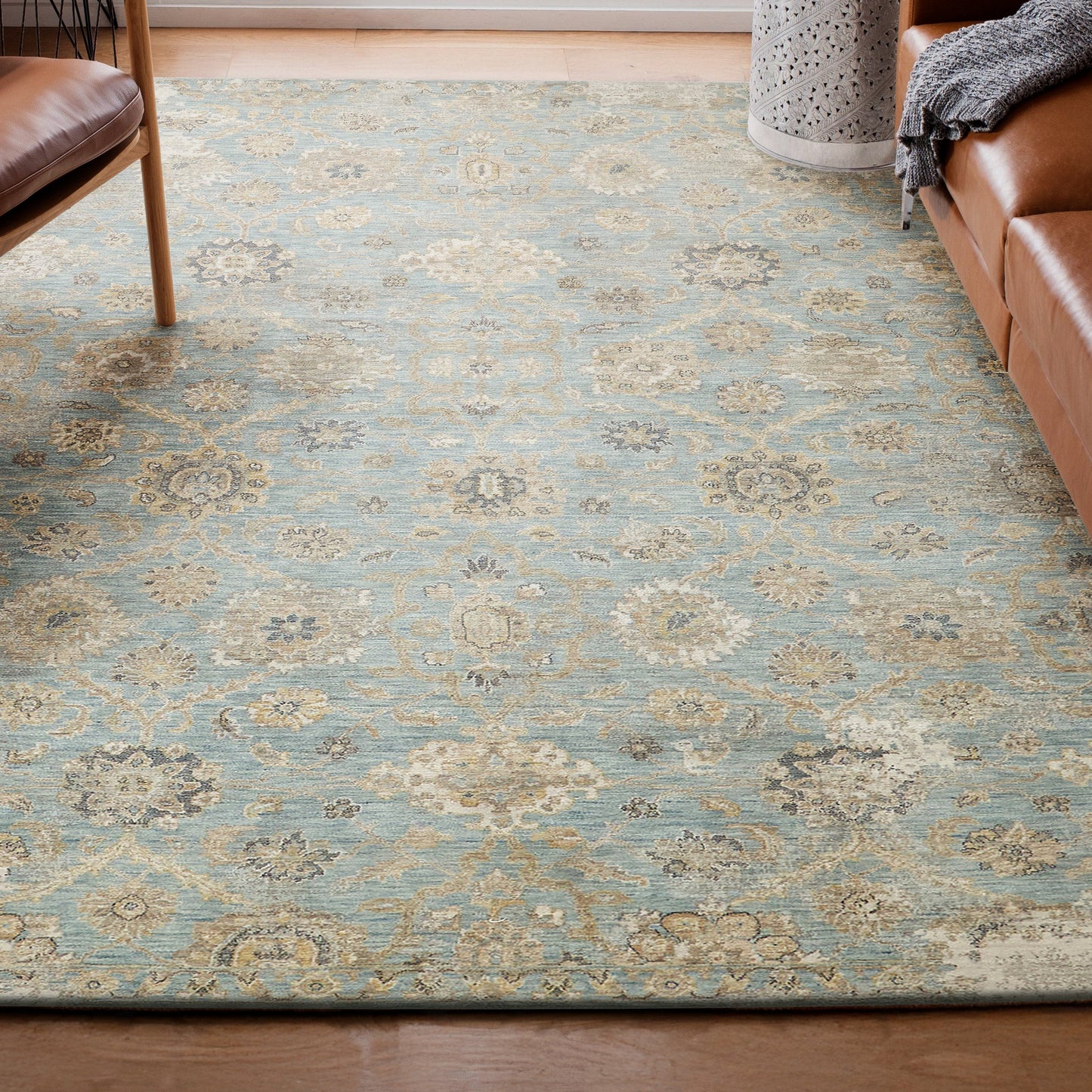 Blue and cream traditional rug with floral medallions, rectangular, in a living room beside a brown leather sofa and chair.