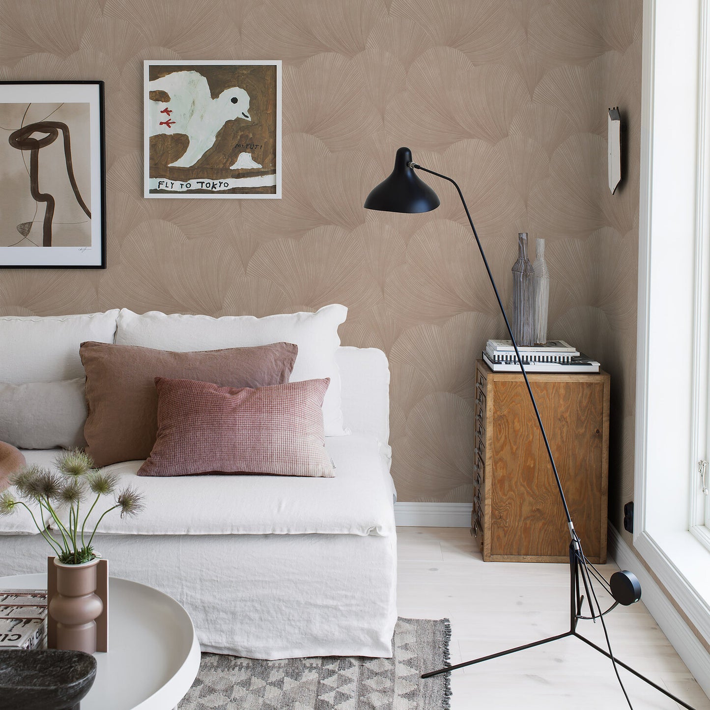 Cozy living room with clay wallpaper on the walls, a white slipcovered sofa with brown and pink cushions, a black arc floor lamp, and a wooden side table.