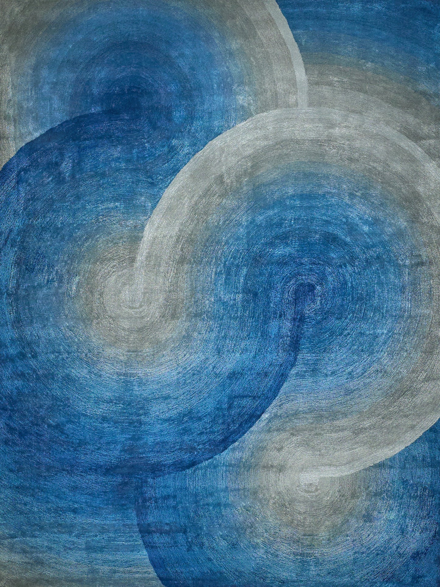 Abstract blue and gray circular swirl pattern; hand-tufted rug with layered rings.