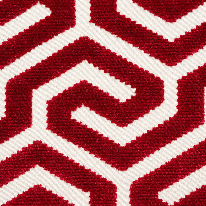 Close-up of a plush area rug with bold red geometric zigzag pattern on white background.