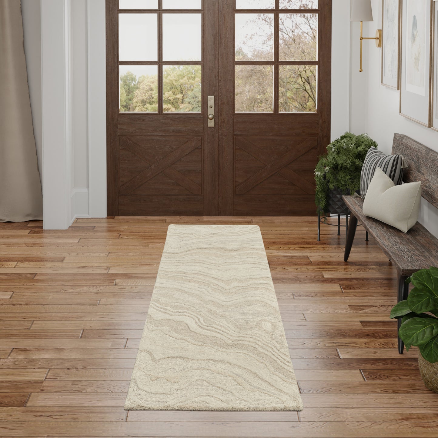 Cream beige hallway runner rug with a subtle wavy pattern on a hardwood floor in an entryway with a bench and potted plants.