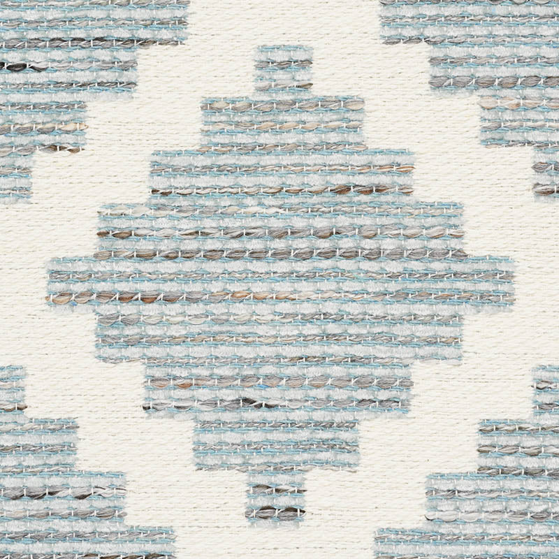 Woven rug with blue-gray geometric diamond motif on cream background; textured kilim-style textile.