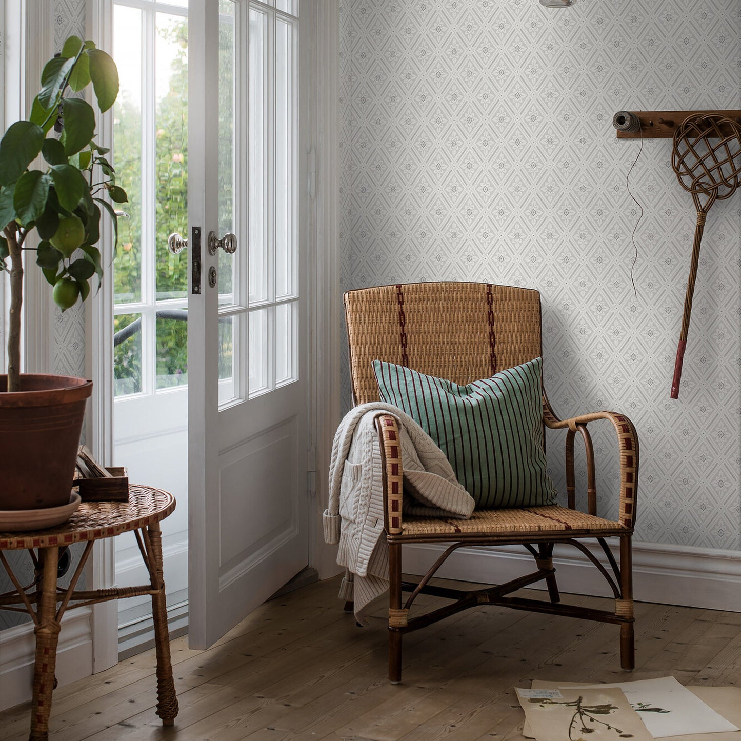 Grey patterned wallpaper in a sunlit room with a tall plant.