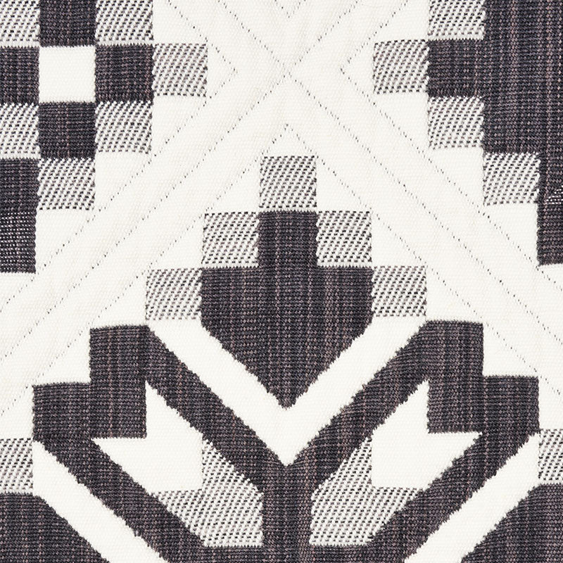 Black and white geometric quilt-block textile with chevrons and a star-like central motif.