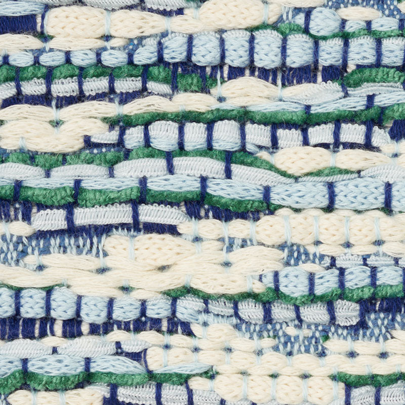 Close-up of a woven textile with cream, blue, and green yarns in chunky stitches and textured stripes.