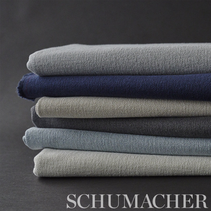 Stack of folded plush terry towels in grey, navy, beige, and blue on a dark backdrop.