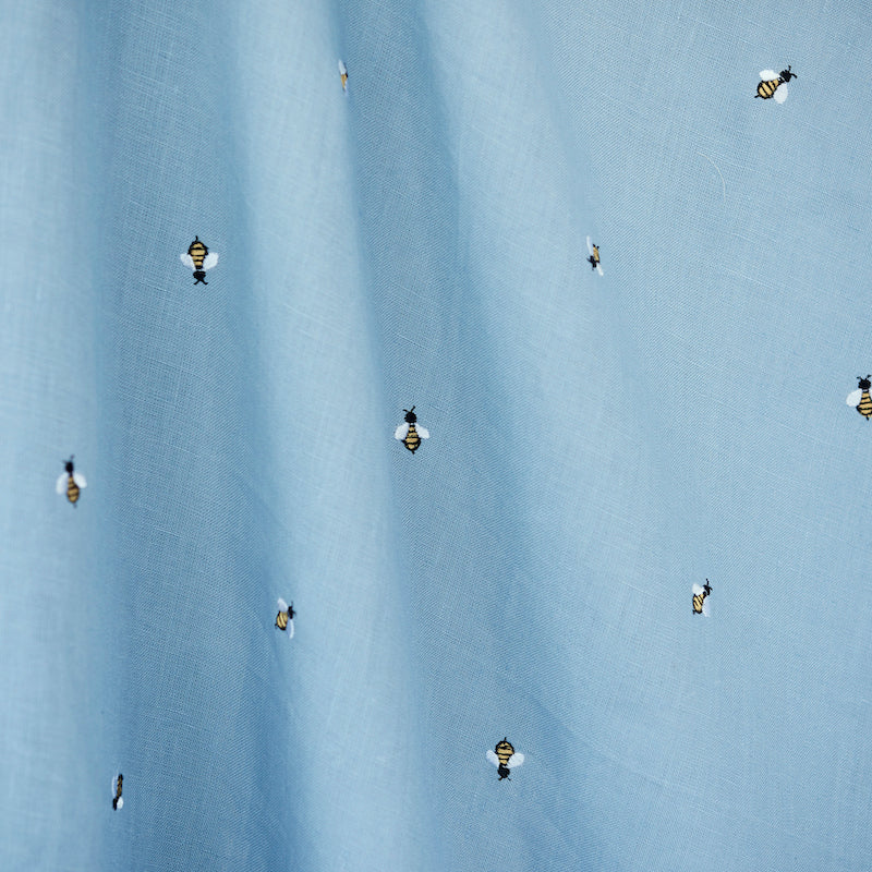 Light blue fabric with tiny honey bee embroidery scattered across.