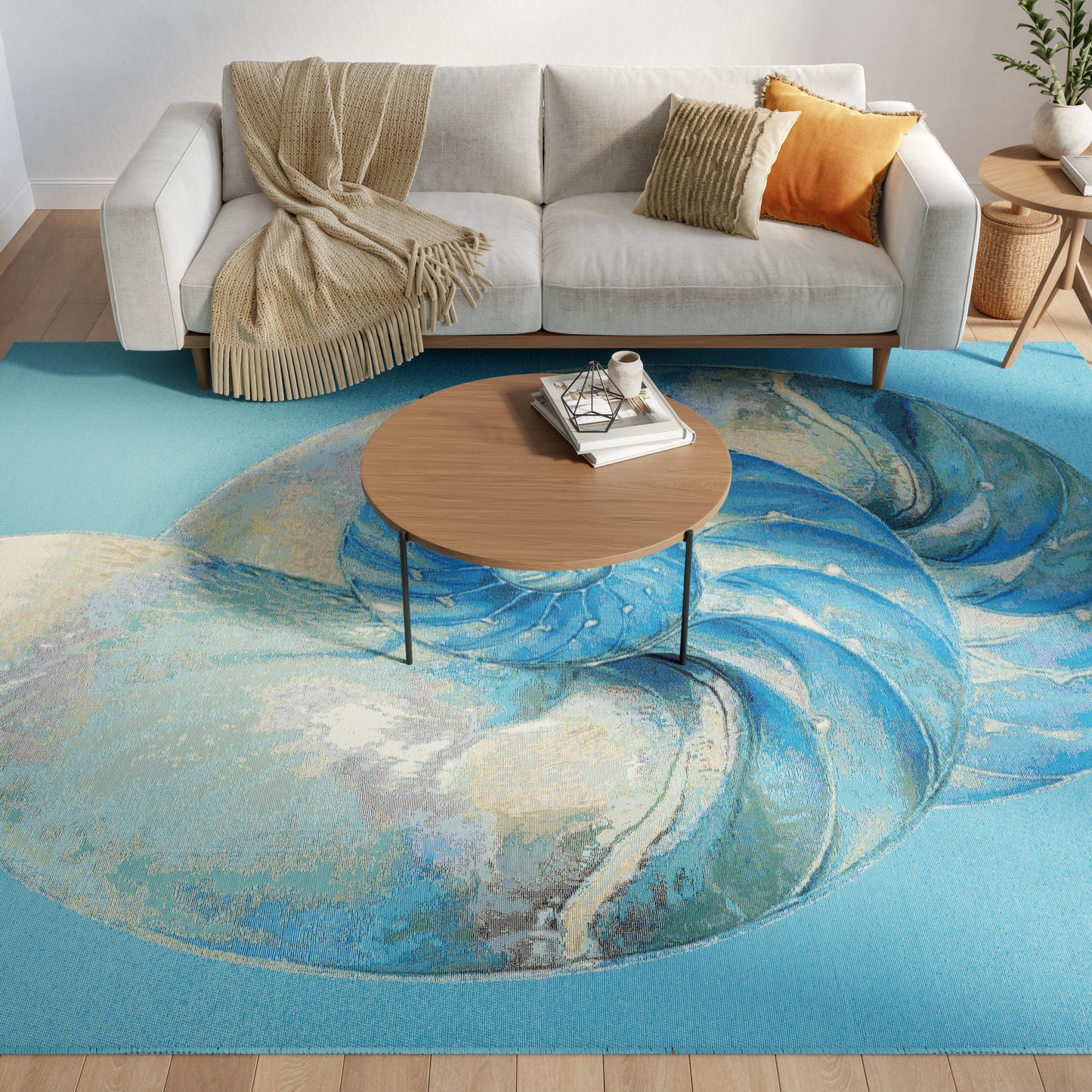 Living room with light gray sofa, beige throw, orange cushion; round wood coffee table on a blue swirl rug.