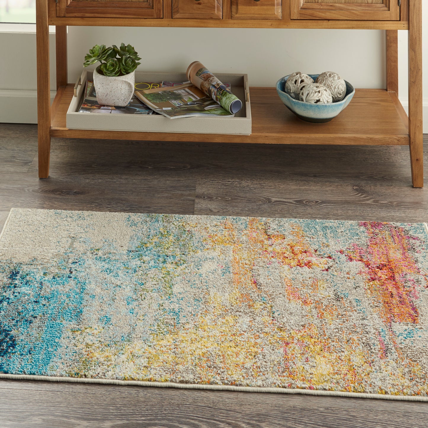 Abstract multicolor area rug with beige base; blue, yellow, orange, pink splashes add modern warmth to living room.