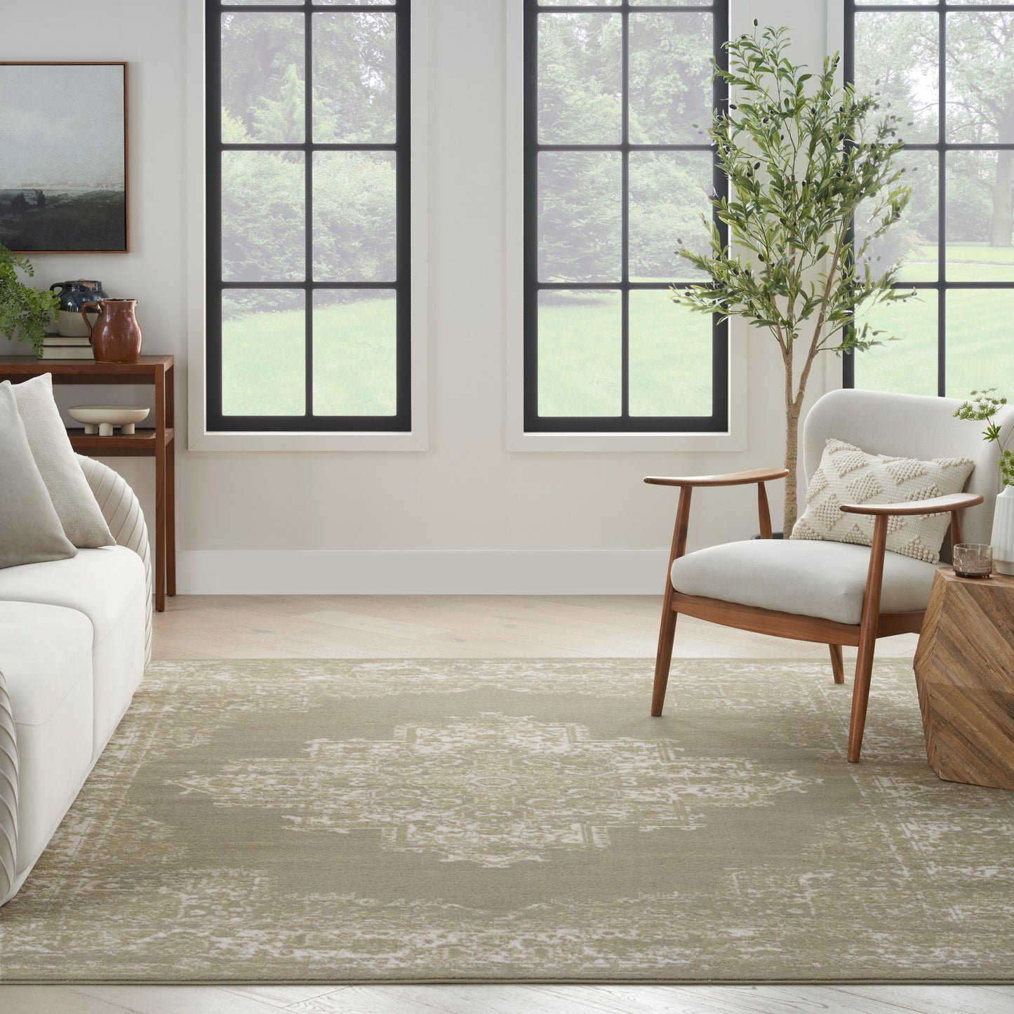 Neutral living room with beige patterned rug, mid-century wooden chair, white sofa, potted plant, and black-framed windows.