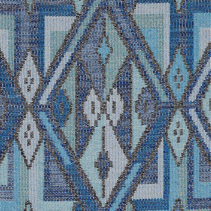 Close-up of kilim-style woven fabric in blues and teals with white diamond geometric motifs.