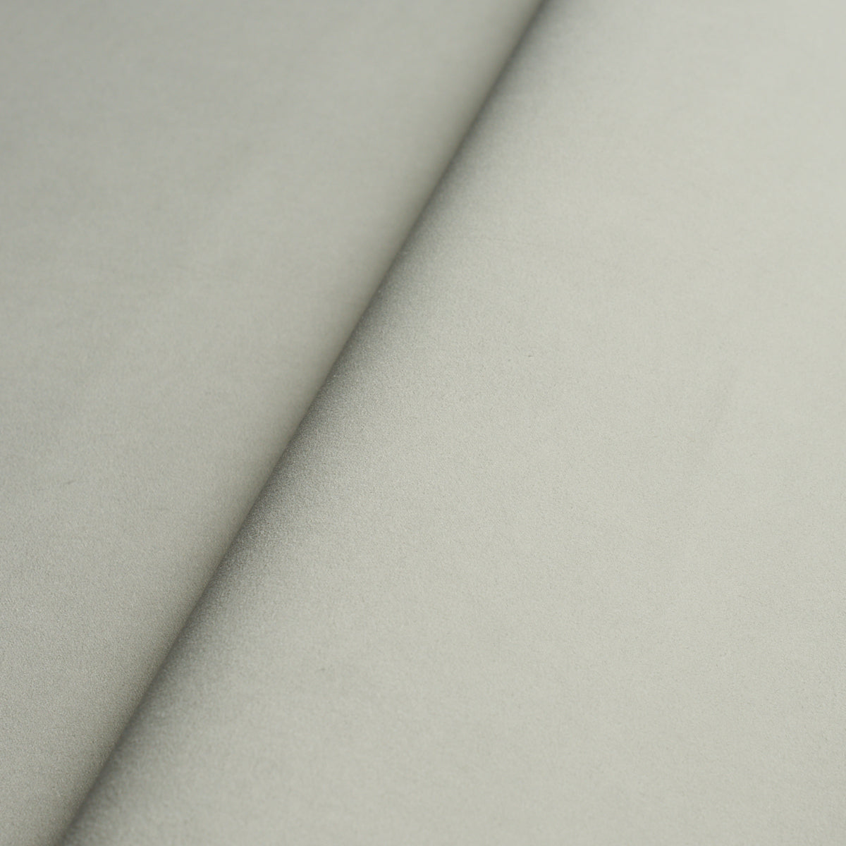 Beige suede-like fabric swatch with a diagonal seam, soft nap; ideal for upholstery or fashion.