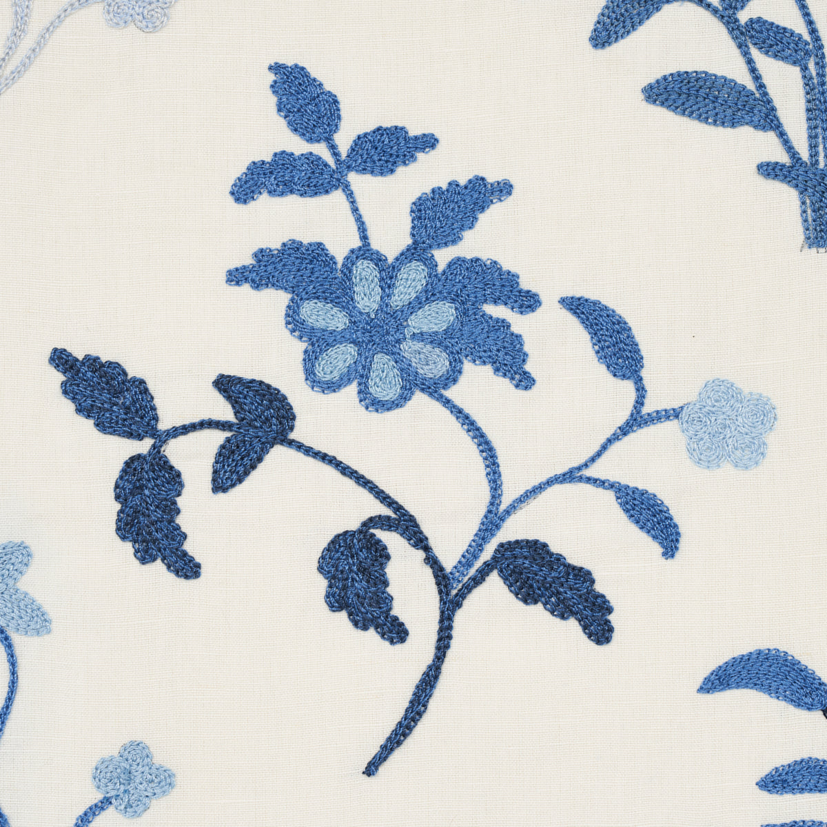 Cream fabric with blue embroidered floral pattern; Navy and light-blue blossoms and stems.
