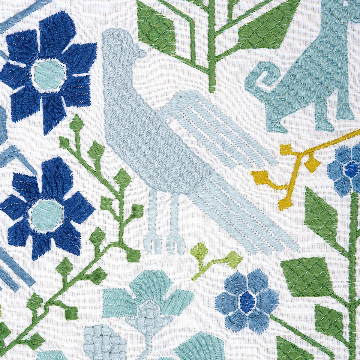 Embroidered textile pattern with a light blue bird, blue flowers, green leaves and geometric botanical motifs.