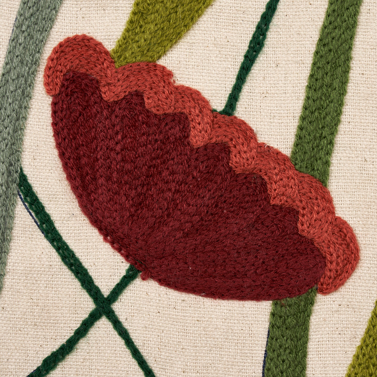 Scalloped-edged red burgundy flower petal embroidery on beige fabric with green leafy stems.