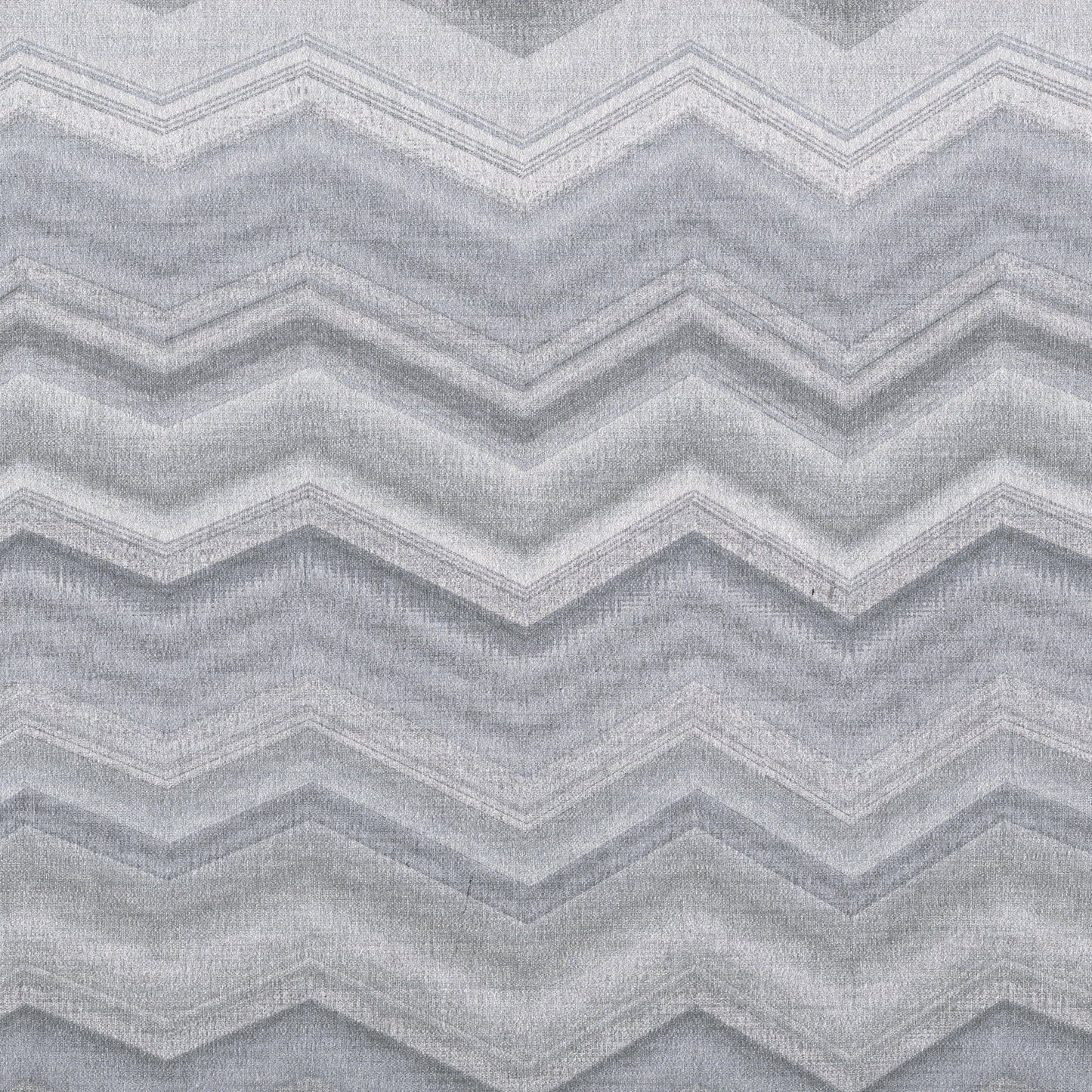Light gray chevron rug with alternating zigzag bands and soft woven texture; modern geometric decor.