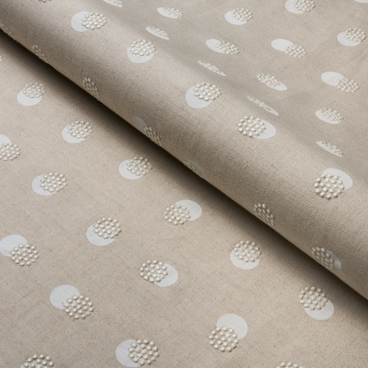 Beige linen‑like fabric with white circular dot clusters, soft drape and subtle texture.
