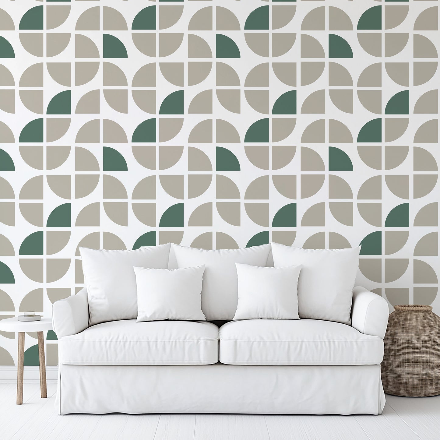 Taupe modern geometric crescent wallpaper on the wall behind a white fabric sofa with four white cushions; side table and woven basket nearby.
