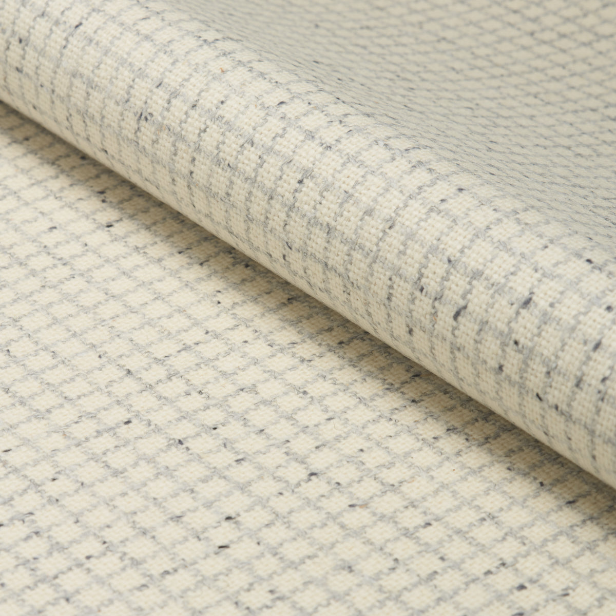 Cream linen-like woven fabric with subtle gray grid pattern, rolled, ideal for upholstery or drapery.