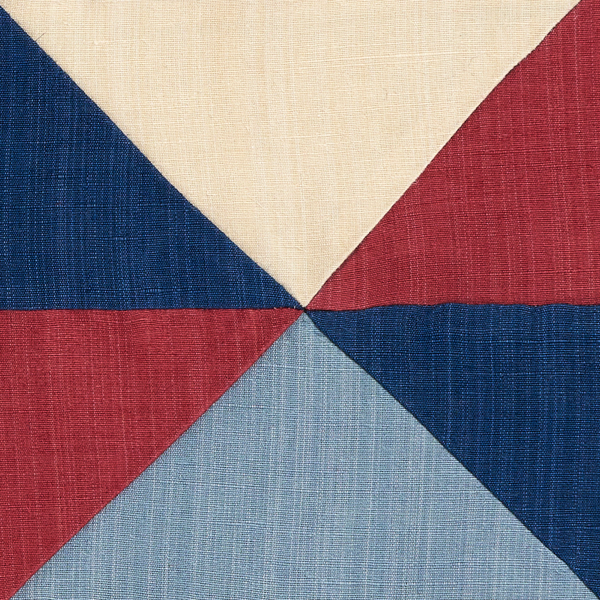 Woven fabric featuring a pinwheel pattern in cream, red, navy & light blue triangles converging at the center.