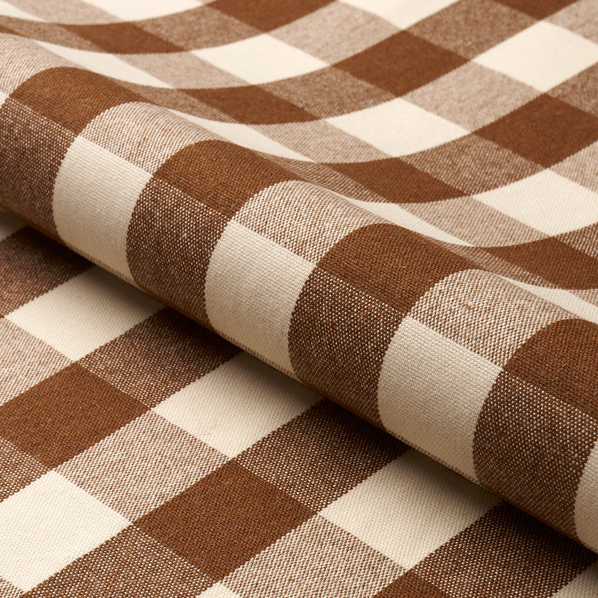 Brown and cream gingham cotton fabric, folded to reveal bold checked pattern; ideal for shirts or table linens.