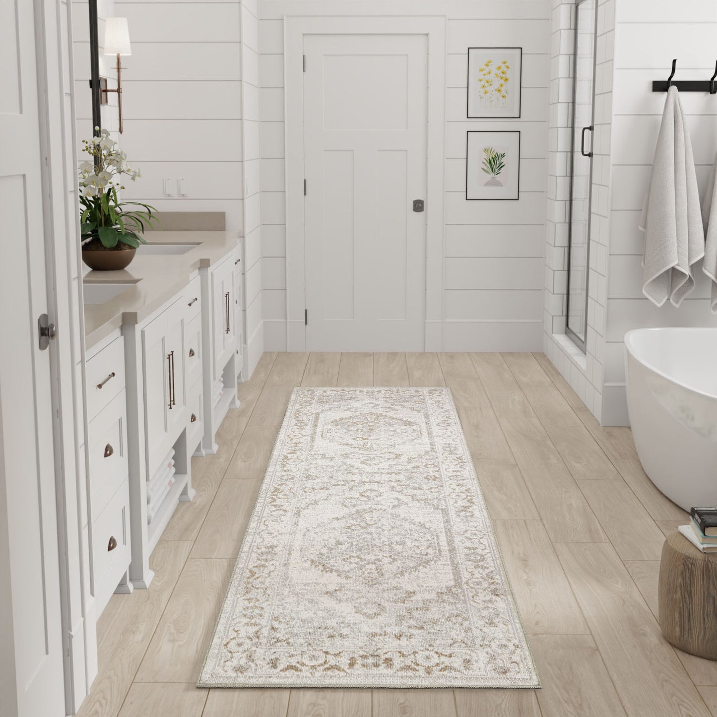 Beige ornate long runner rug on light wood floor in a white bathroom with cabinetry and a freestanding tub.