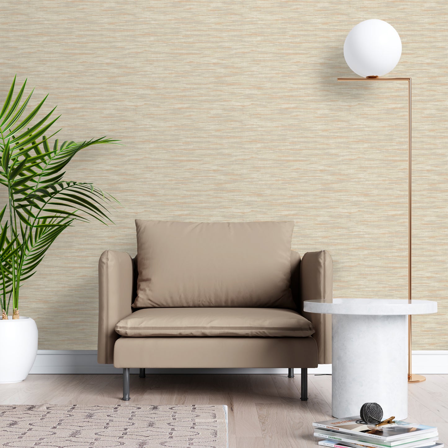 Beige armchair in a room with textured wallpaper, tall copper floor lamp, round marble side table, and a potted plant.