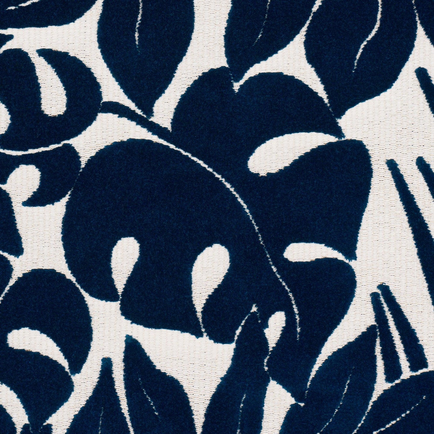 Navy blue leaf pattern on cream fabric, bold botanical textile design.