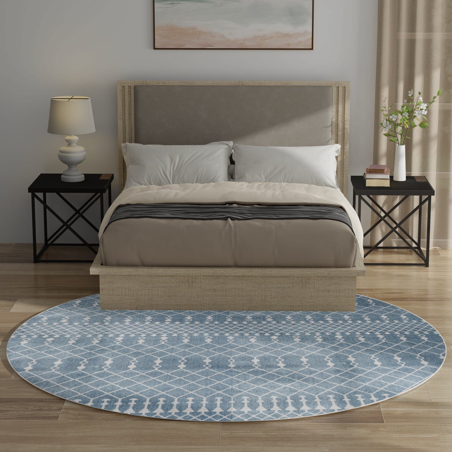 Beige upholstered bed with neutral bedding, black metal nightstands, lamp, blue lattice rug, plant and books by window.