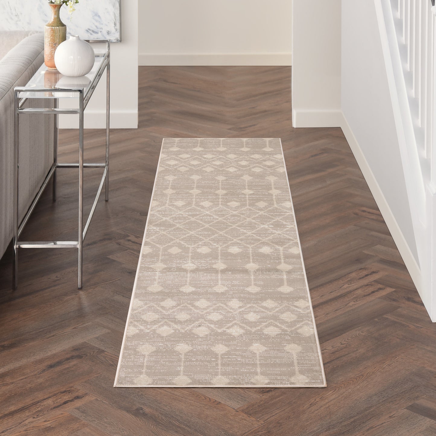 Beige geometric runner rug with diamond & circle motifs in a modern hallway with dark herringbone flooring.