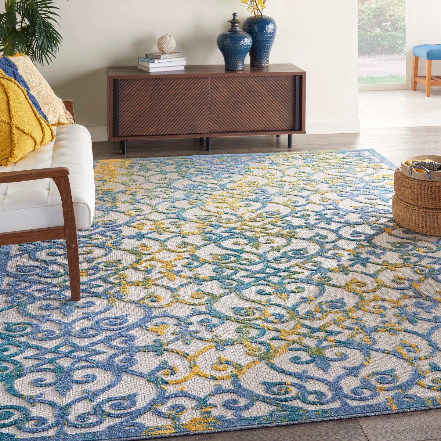 Patterned area rug with blue, teal and yellow scroll motif in a contemporary living room setting.