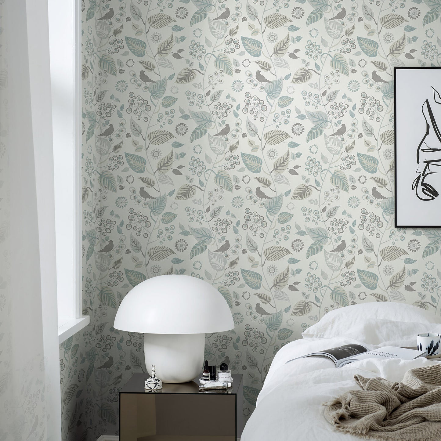 Bedroom with pale botanical wallpaper, white ceramic mushroom lamp on dark bedside table, white bedding.