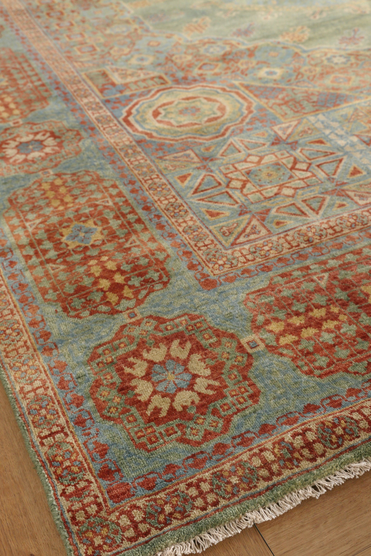 Rectangular turquoise and red oriental area rug with geometric medallions, decorative borders and fringe.