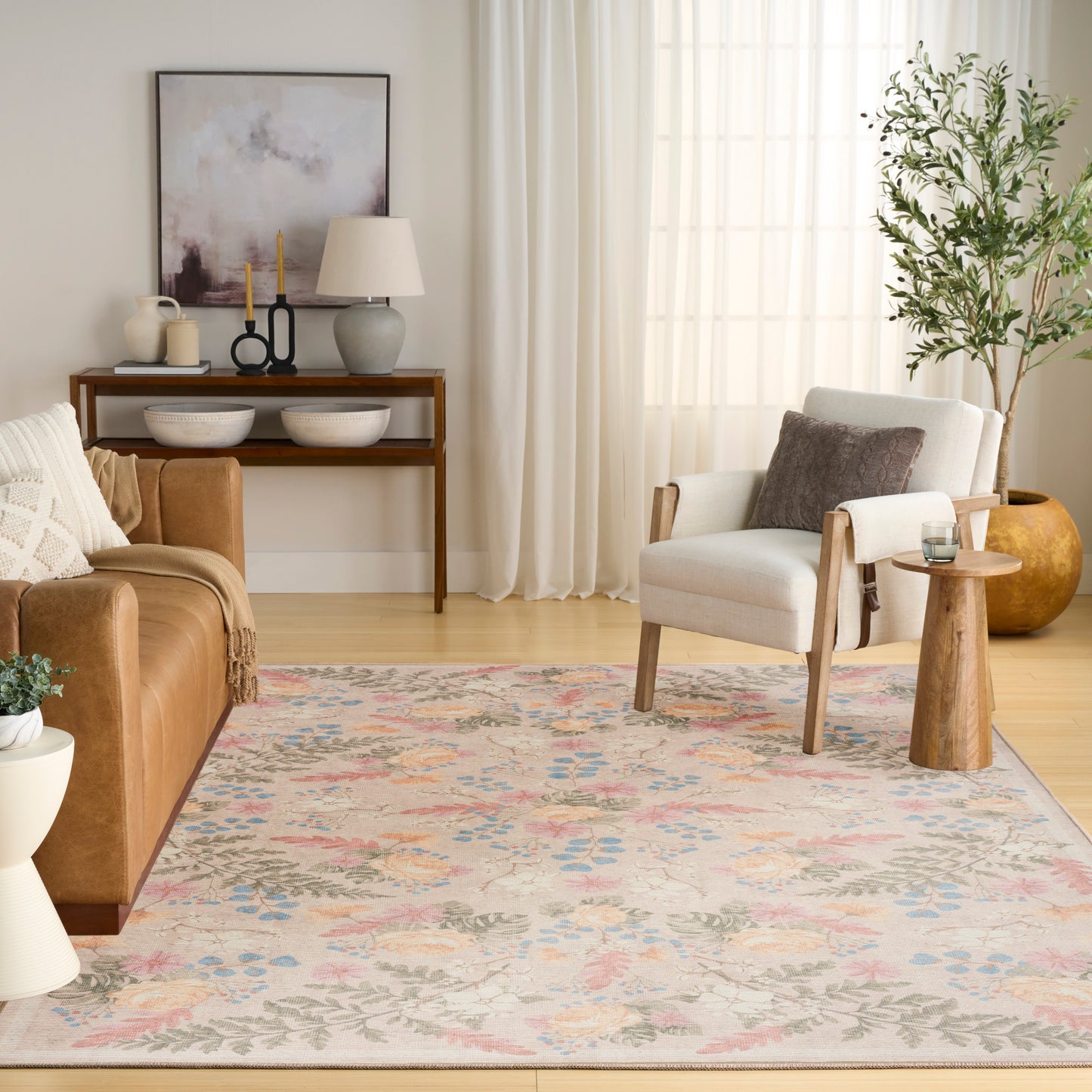 Cozy living room with a pastel floral rug, cream armchair, brown leather sofa, and a wooden console with abstract art.