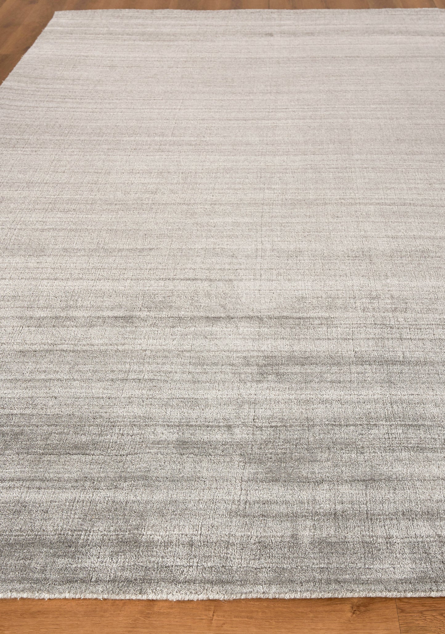 Light gray hand-loomed indoor rug, 2' x 3', with subtle tonal stripes on a hardwood floor; contemporary, versatile living room accessory.