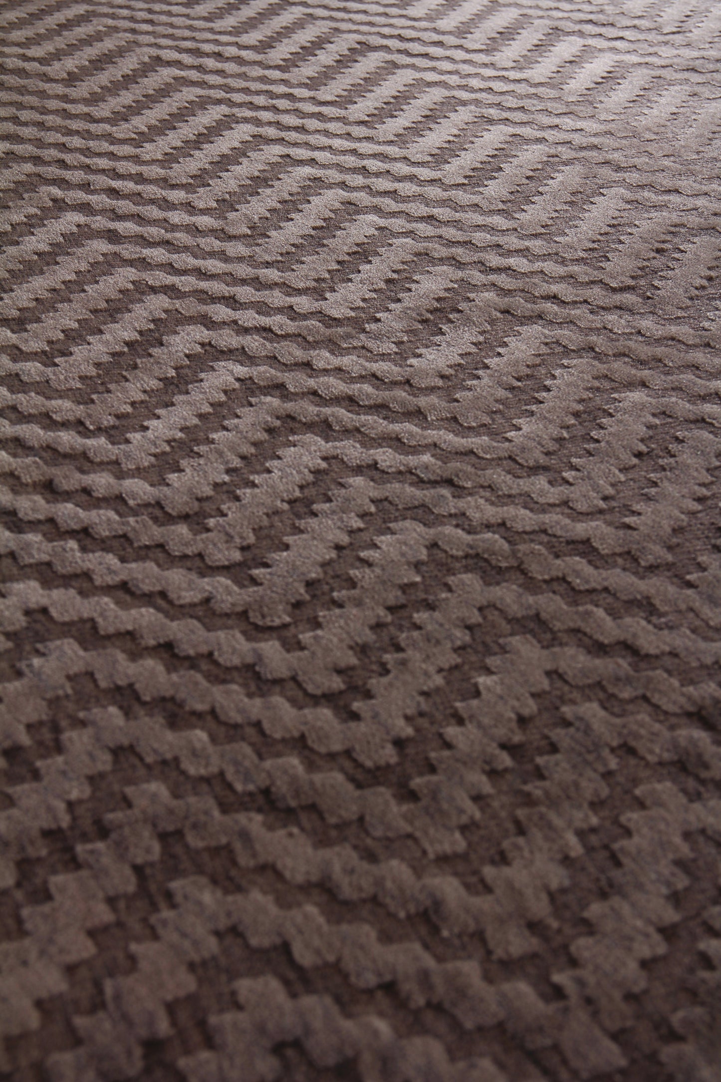 Brown textured rug with raised chevron zigzag pattern and plush pile.