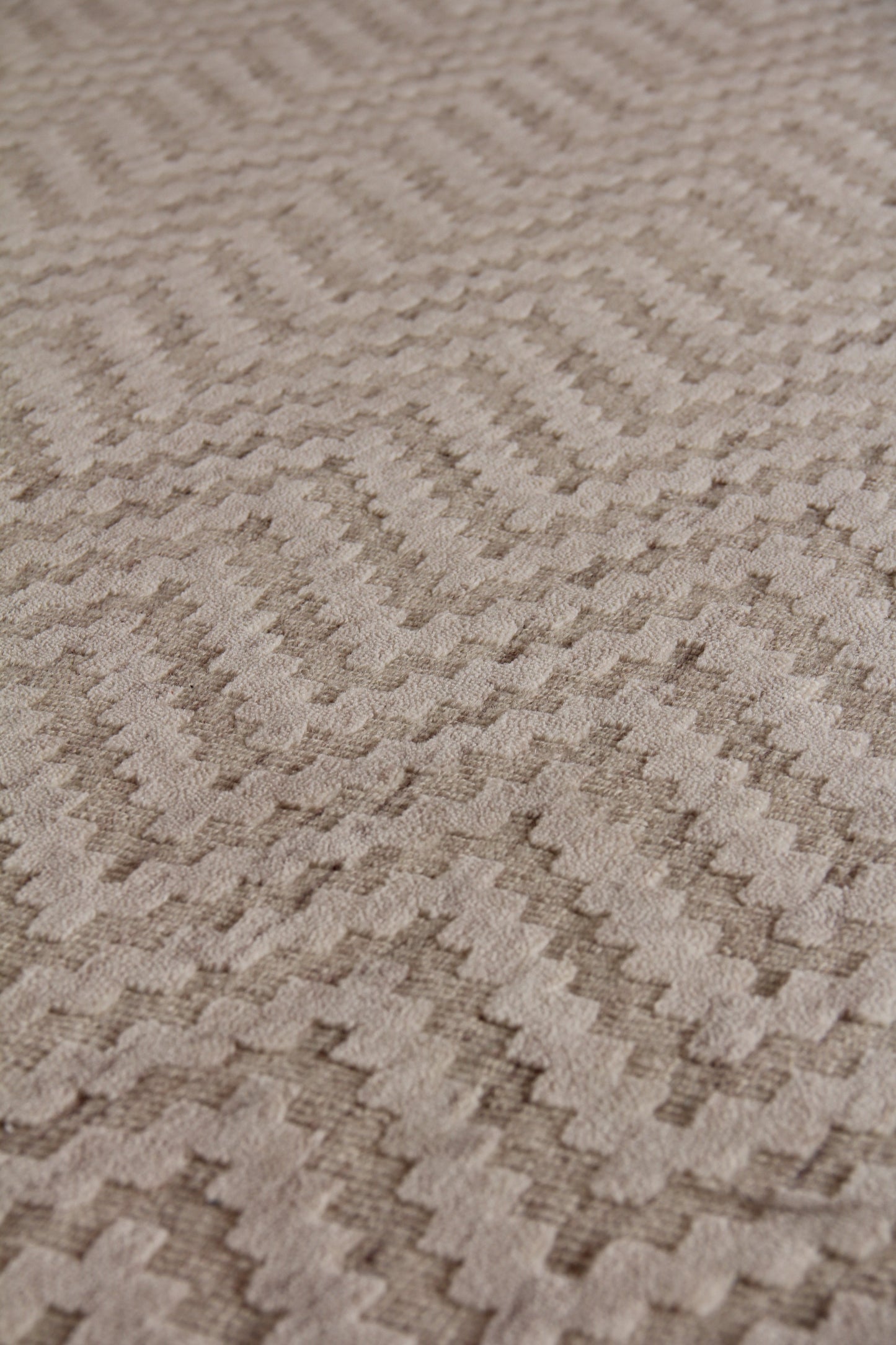 Beige indoor hand loomed rug with a raised zigzag chevron pattern and plush textured weave.