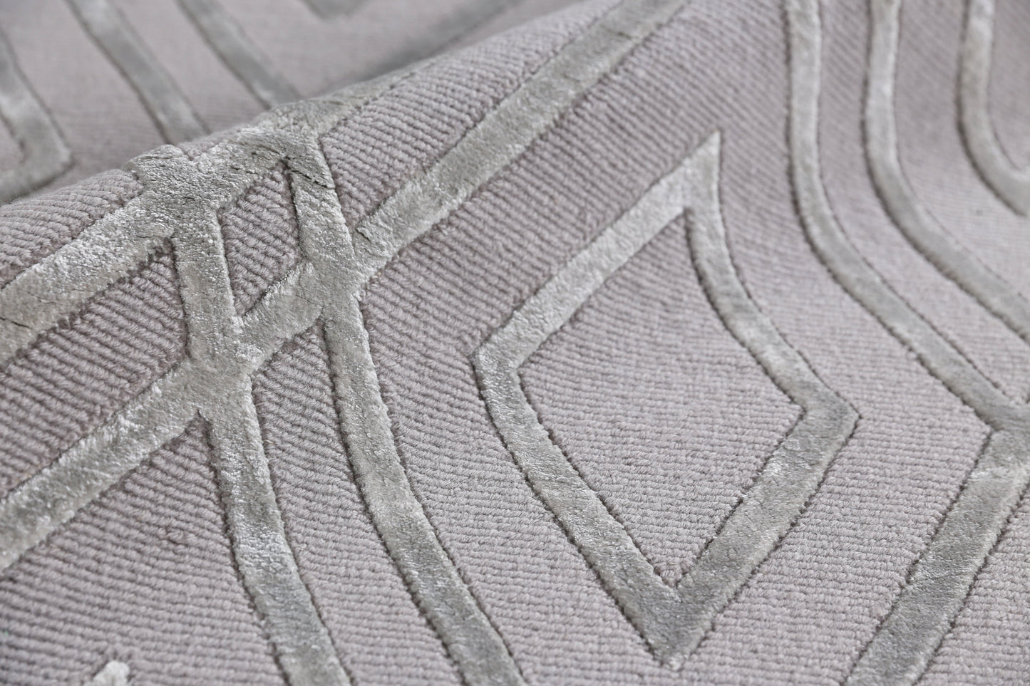 Soft light-gray hand-knotted rug with raised diamond motifs and subtle sheen.
