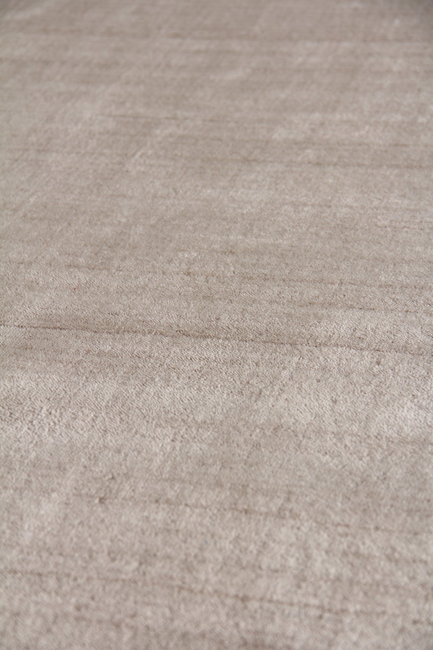 Beige textured rug close-up with soft, looped pile in neutral tones.