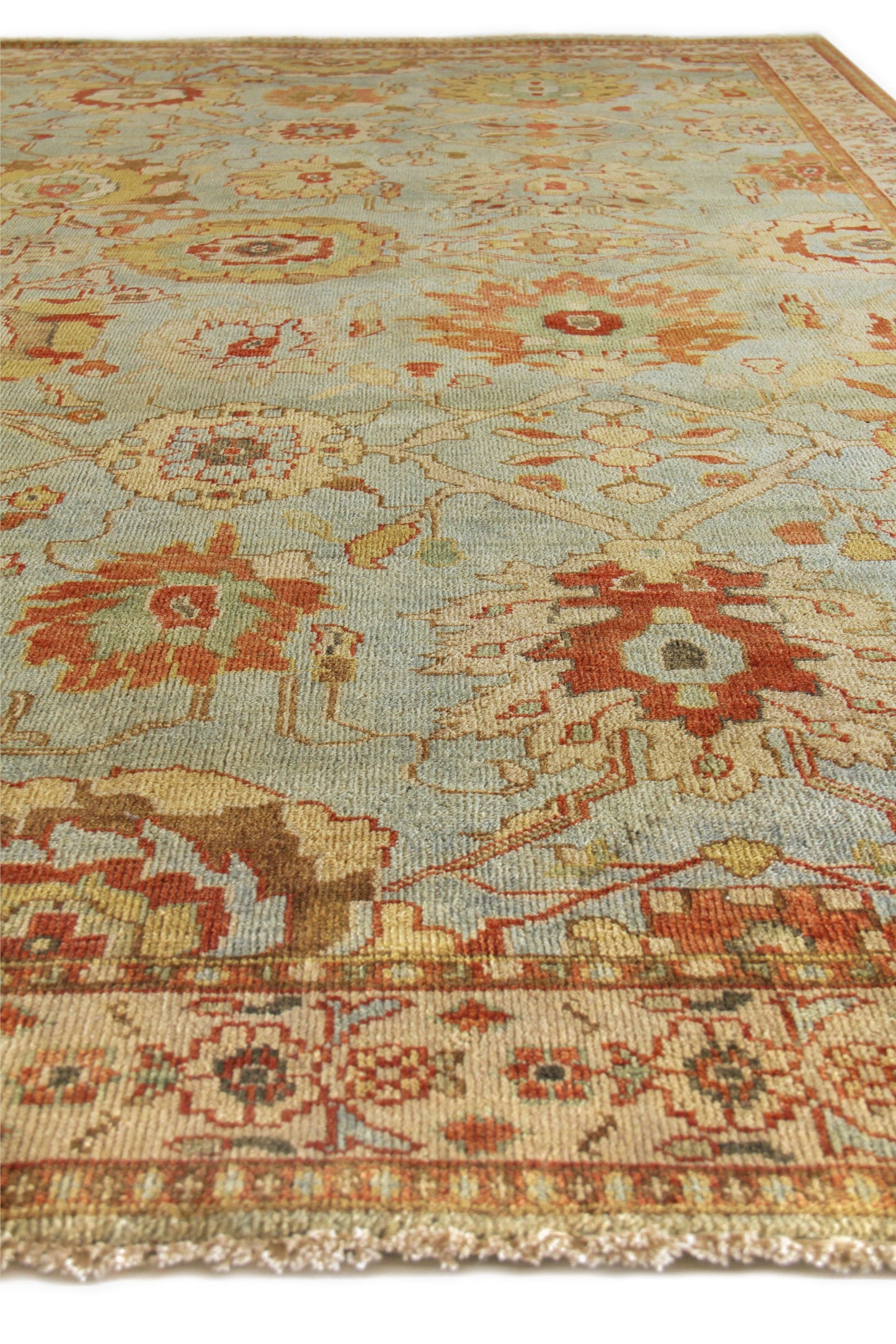 Light blue Oriental rug with red, yellow floral motifs, bordered trim and fringed edges.