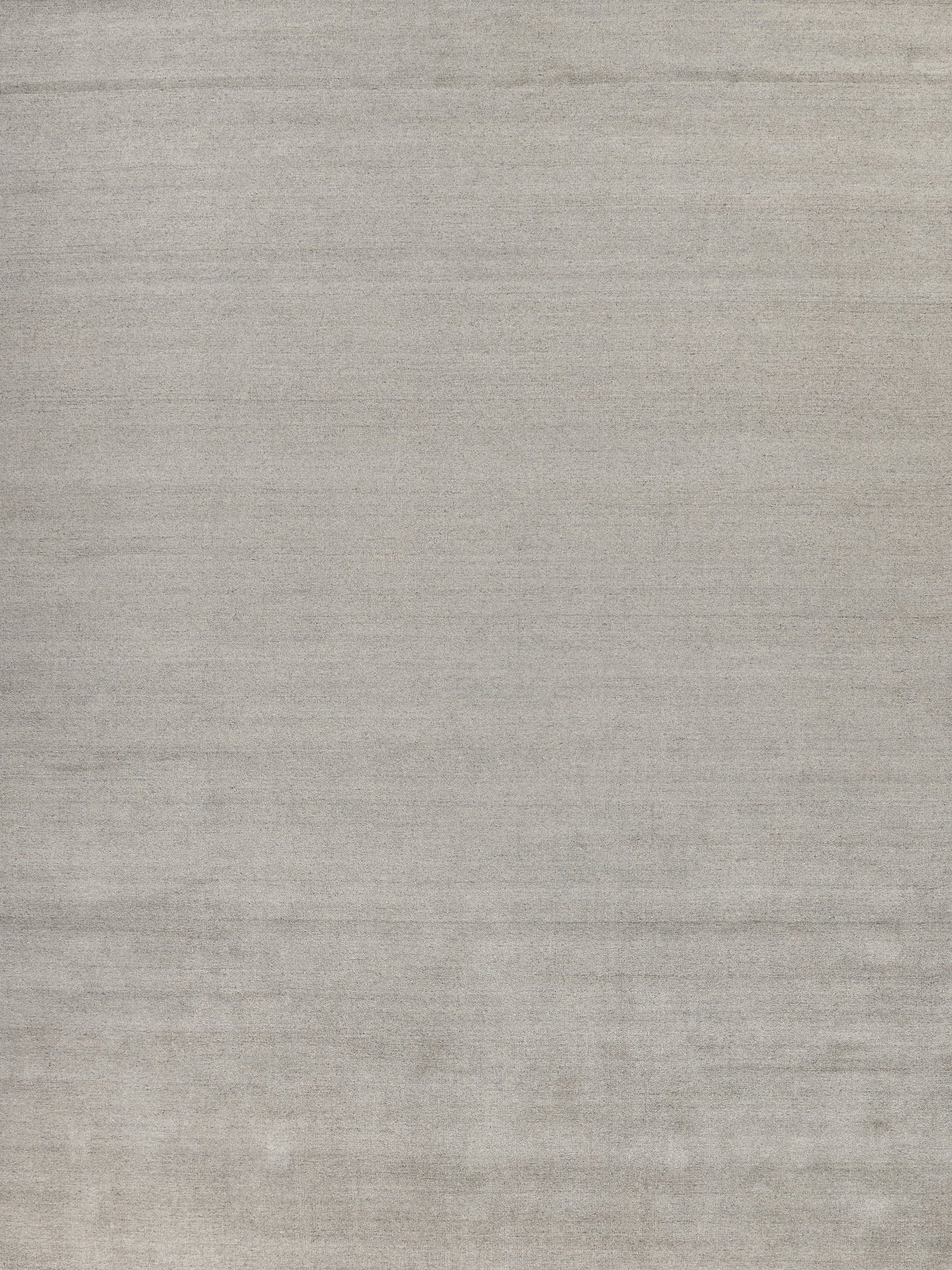 Neutral light grey hand-loomed rug with a textured surface and subtle horizontal streaks.
